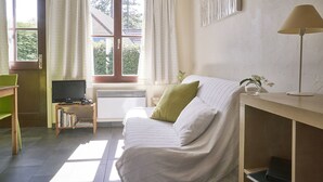 Een gezellige kamer met een bed, een televisie, een bureau en een raam met gordijnen.