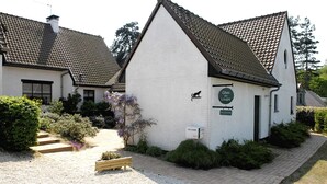 Een wit gebouw met een pannendak, een bankje en een bordje met de tekst 'Gites des Loups'.