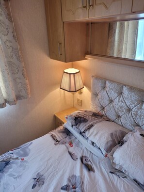 A bedroom with a bed, a nightstand, a lamp, and a wardrobe.