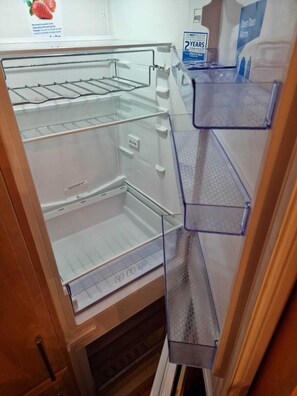 An empty refrigerator with multiple shelves and a freezer compartment.