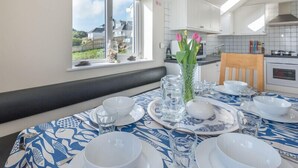 Un comedor con una mesa dispuesta para cuatro personas, un jarrón con flores y vistas al exterior.