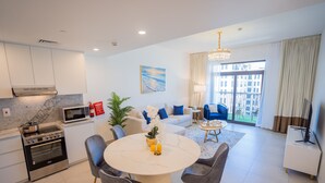 Un salon moderne comprenant un coin repas, une cuisine avec un four encastré et une grande fenêtre offrant une vue sur la ville.