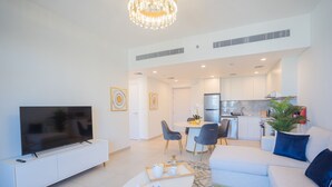 Un salon moderne doté d’un téléviseur à écran plat, d’un canapé blanc, d’une table basse et d’un coin repas avec des chaises et une petite table.
