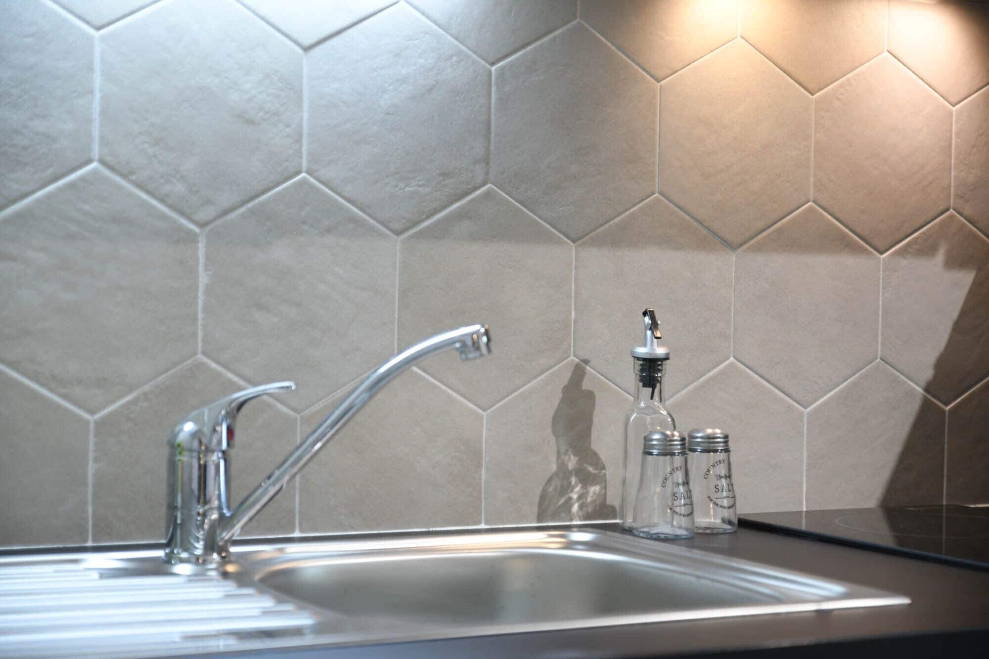 A kitchen sink with a modern faucet and salt shakers on the countertop.