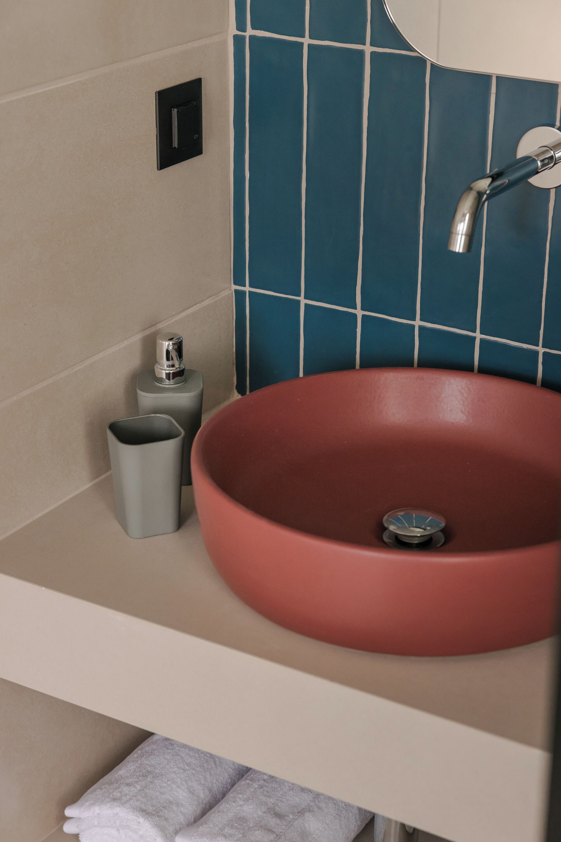 Ein Badezimmer mit einem roten Waschbecken, einem Spiegel, einem Wasserhahn und einem Handtuchhalter.