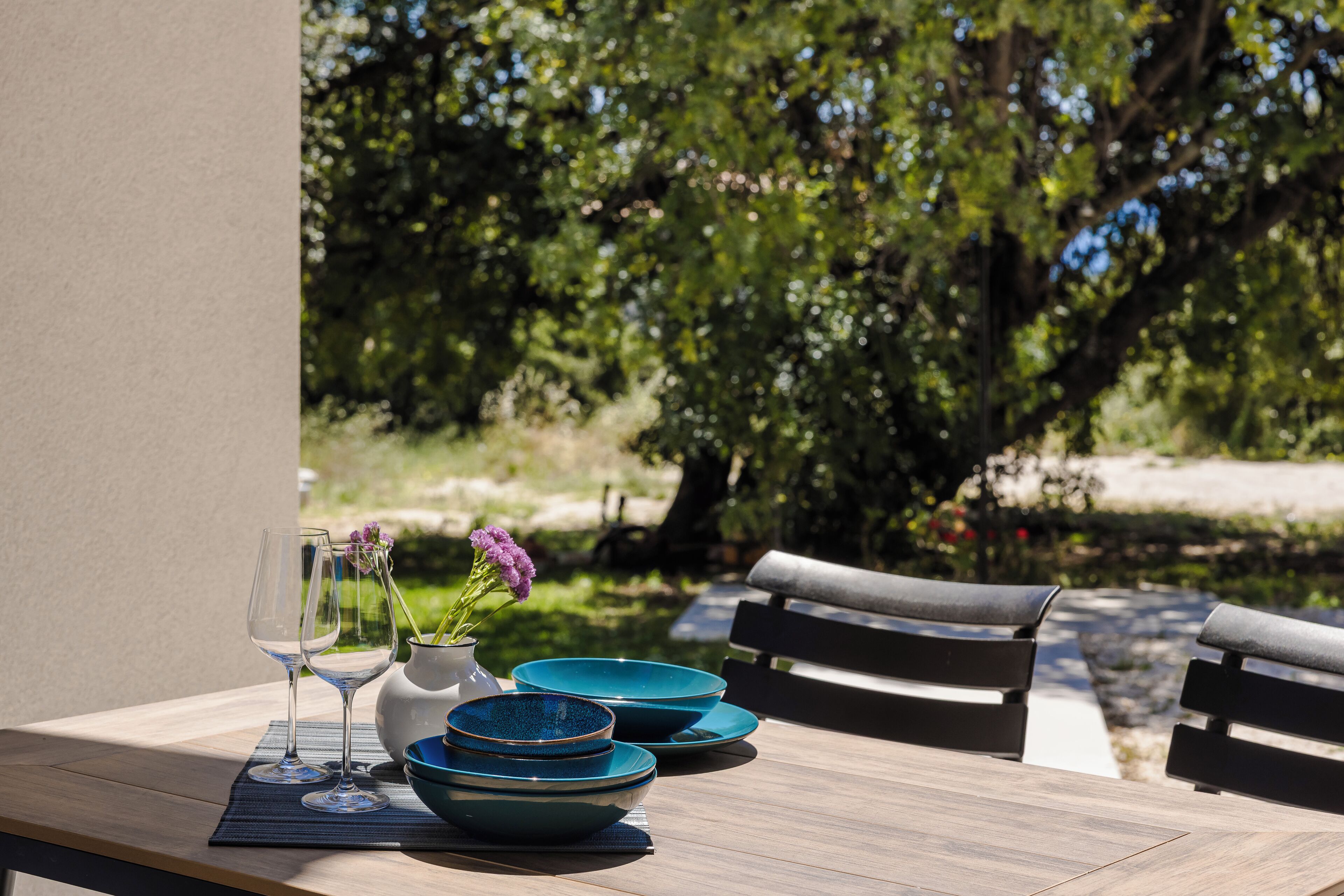 A table with blue bowls, a vase with flowers, and two wine glasses.