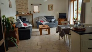Ein Wohnzimmer mit Sofa, Couchtisch, Fernseher und einem Essbereich mit Tisch und Stühlen.