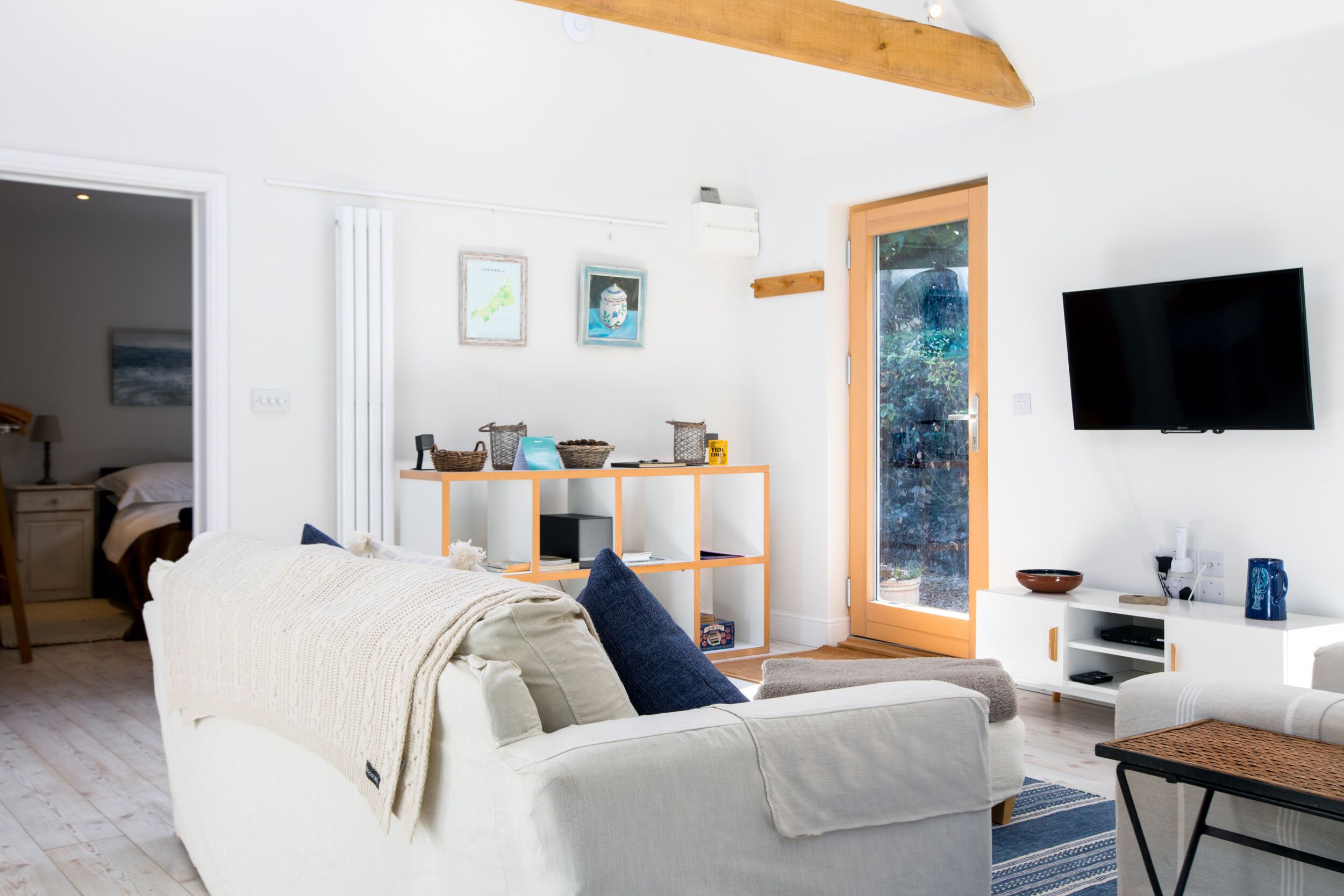 A modern living room with a white sofa, a coffee table, and a TV mounted on the wall.