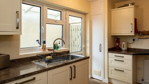 A kitchen with a window, sink, and countertop. - Pencreek (Wadebridge)