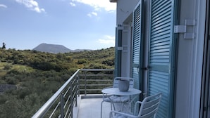 Un balcón con mesa y sillas, con vistas a un paisaje montañoso.
