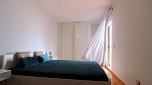 Une chambre à coucher avec un lit, une table de chevet, une armoire et une fenêtre avec des rideaux.