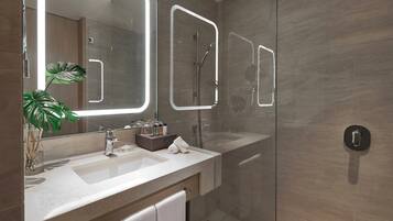 A modern bathroom with a glass shower enclosure, a large mirror with LED lighting, a sink with a vanity, and a potted plant.