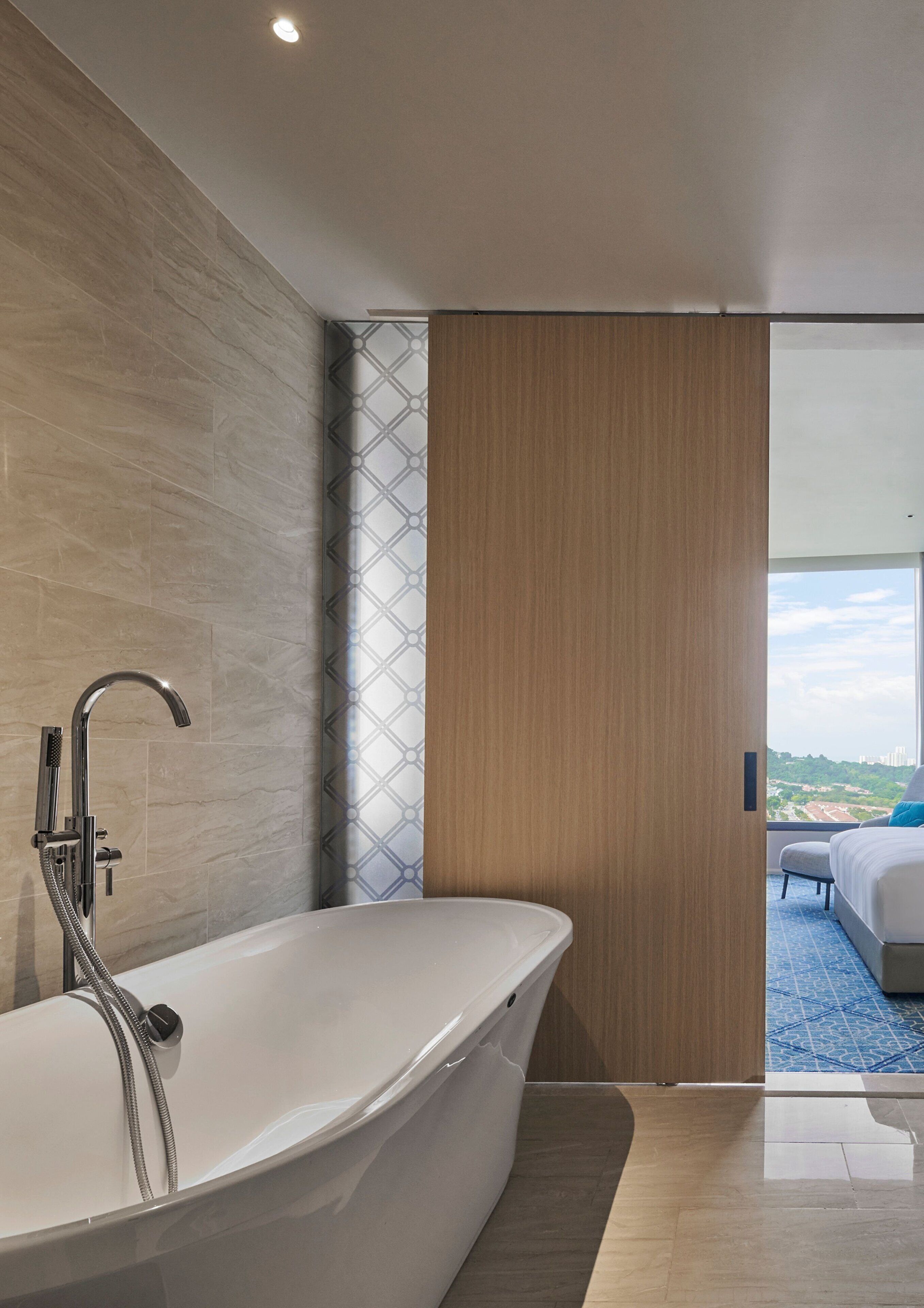 A modern bathroom with a freestanding bathtub, a showerhead, and a patterned wall.