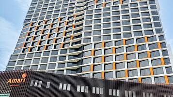 Un edificio moderno de gran altura, con un diseño que incluye una rejilla de ventanas y detalles en naranja.