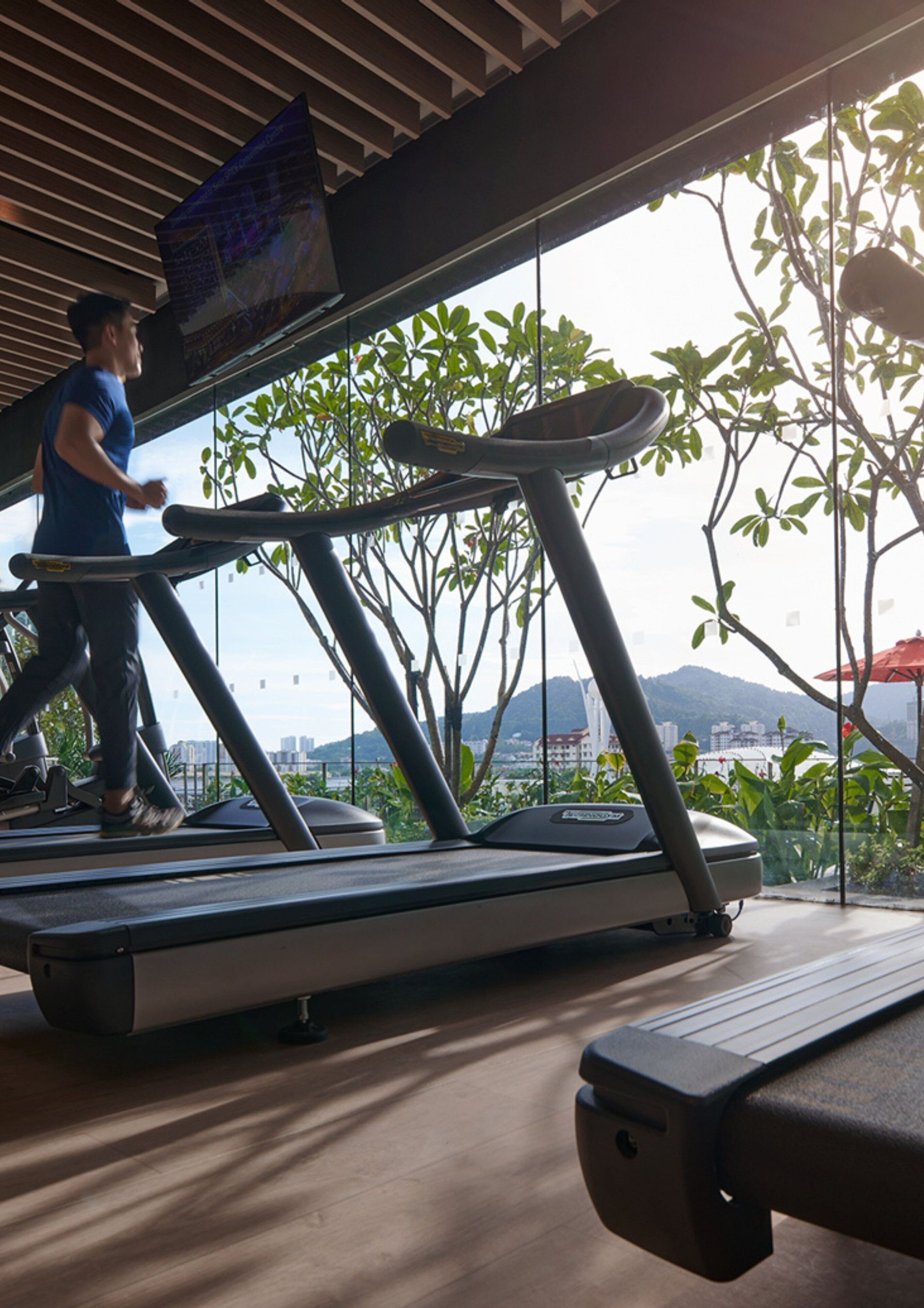 Una cinta de correr en una habitación con vista a un paisaje urbano y montañas.