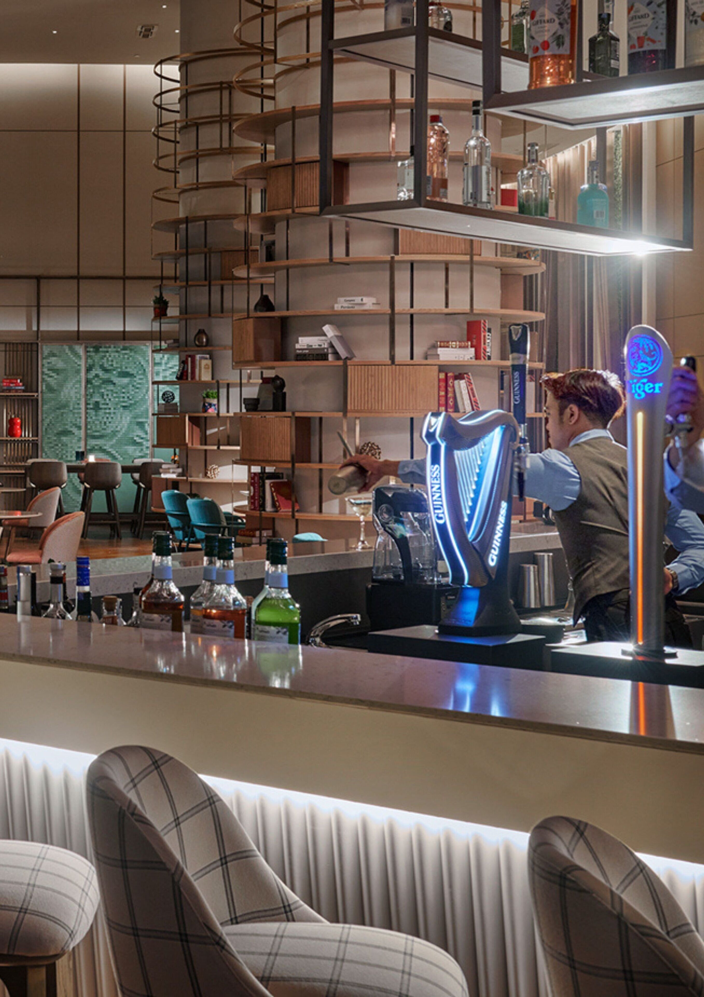 Un espace bar doté d’un distributeur de bière Guinness, de sièges et d’un aménagement intérieur moderne.