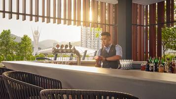 A bar area with a bartender, high chairs, and a view of a cityscape.