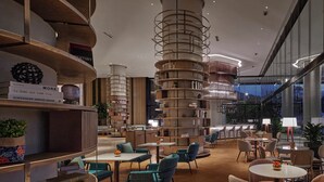 Een moderne bibliotheek met trapvormige boekenkasten, comfortabele zitplaatsen en uitzicht op de stad 's nachts.