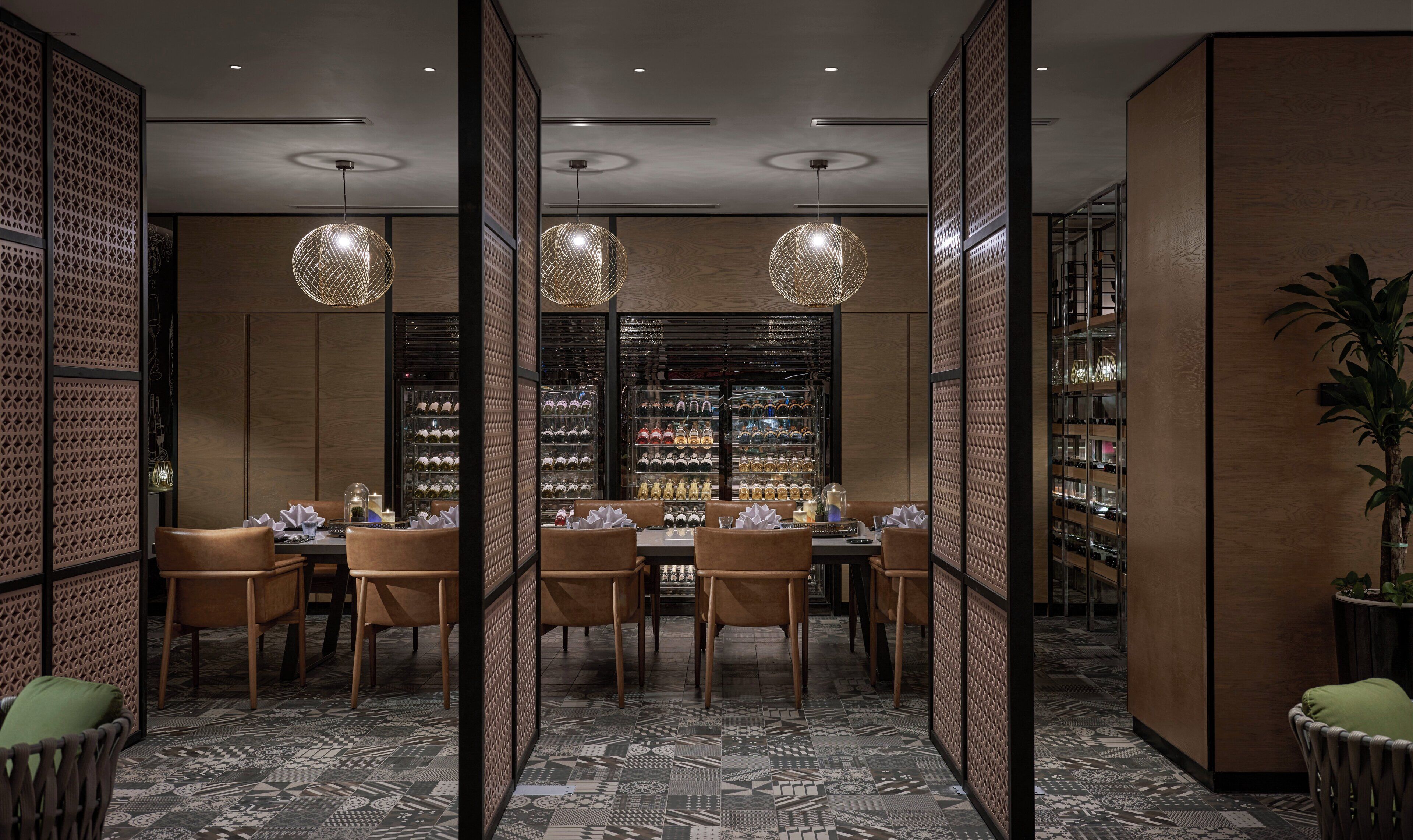 Un espace repas avec une longue table, des chaises et un meuble à vin en arrière-plan.