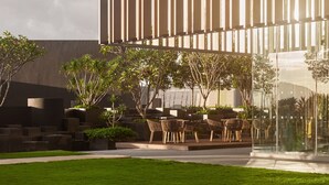 Een modern gebouw met verticale lamellen, terras en groen.