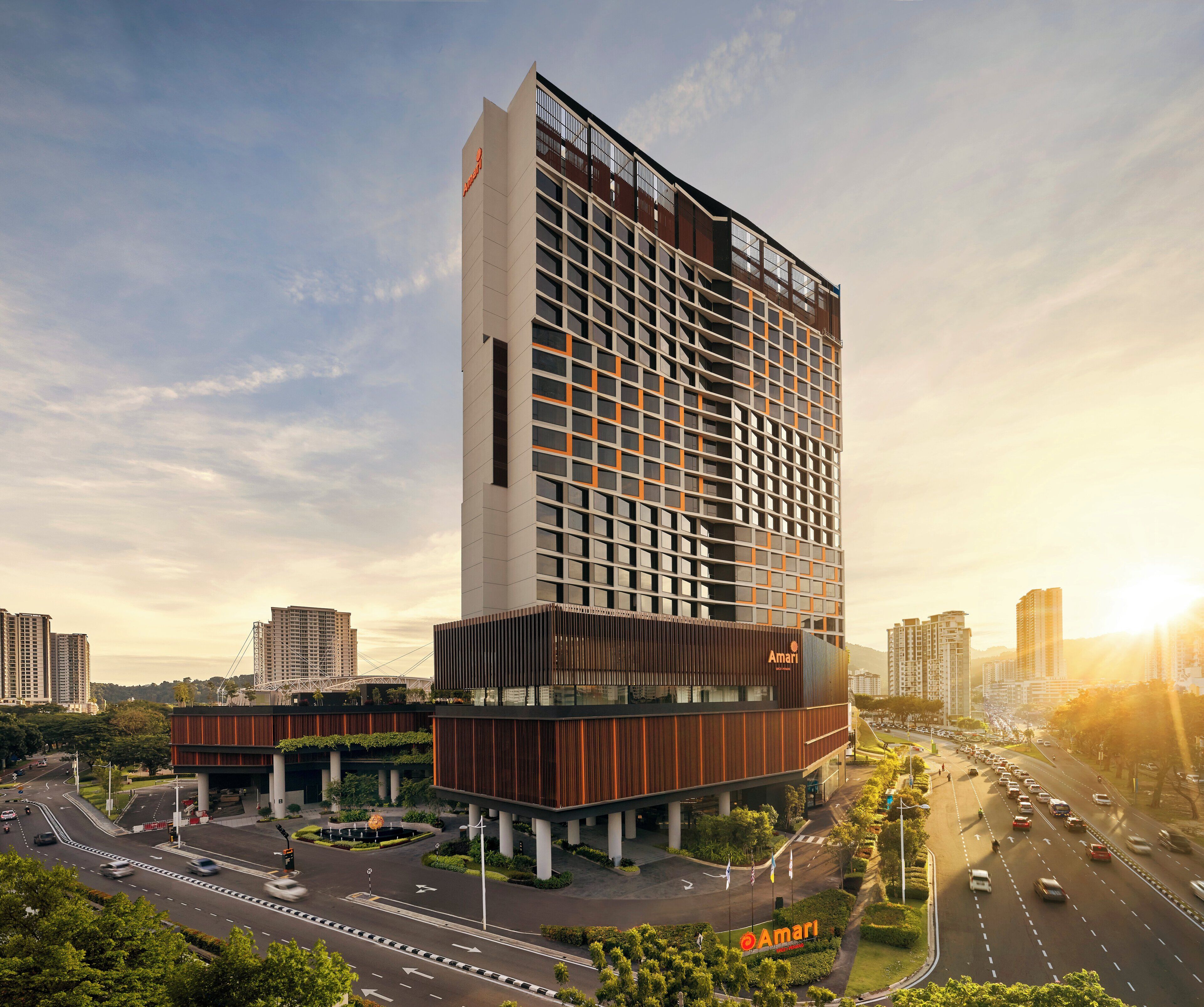 A modern hotel with a prominent glass facade, multiple floors, and a rooftop terrace.