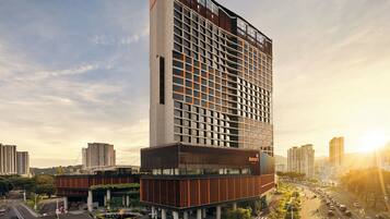 A modern hotel with a prominent glass facade, multiple floors, and a rooftop terrace.