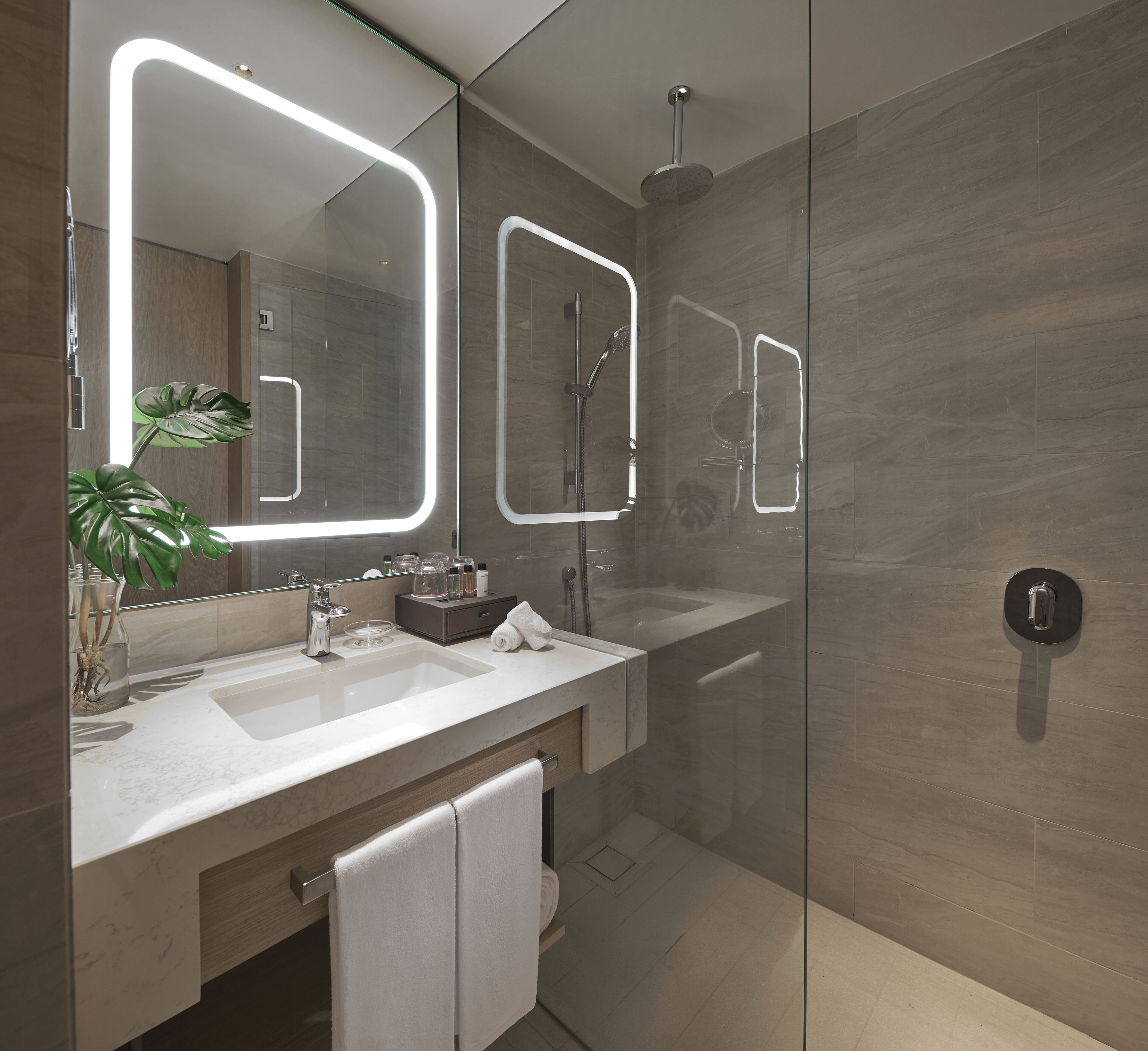 A modern bathroom with a large mirror, a shower, and a sink.