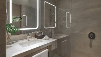 A modern bathroom with a large mirror, a shower, and a sink.