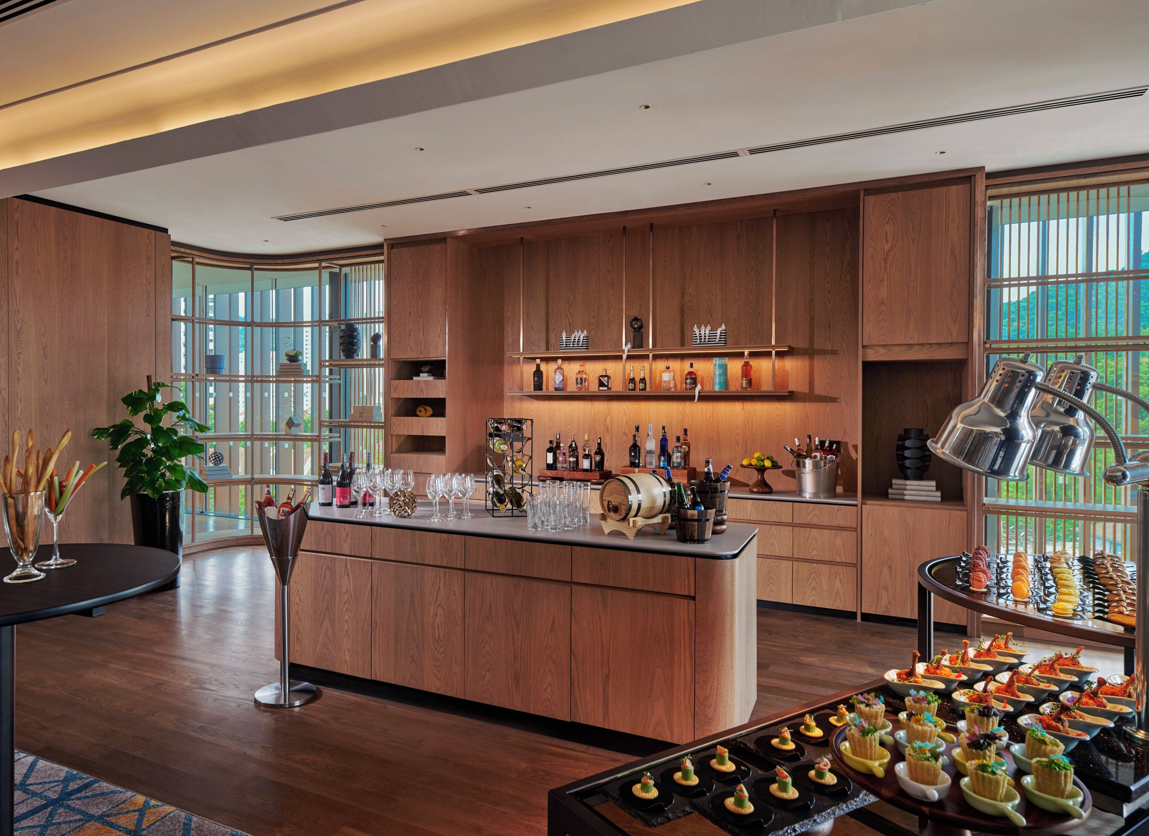 Una cocina moderna con armarios de madera, una isla central con utensilios de bar, y una variedad de botellas y vasos.