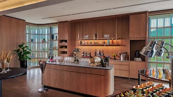 Una cocina moderna con armarios de madera, una isla central con utensilios de bar, y una variedad de botellas y vasos.