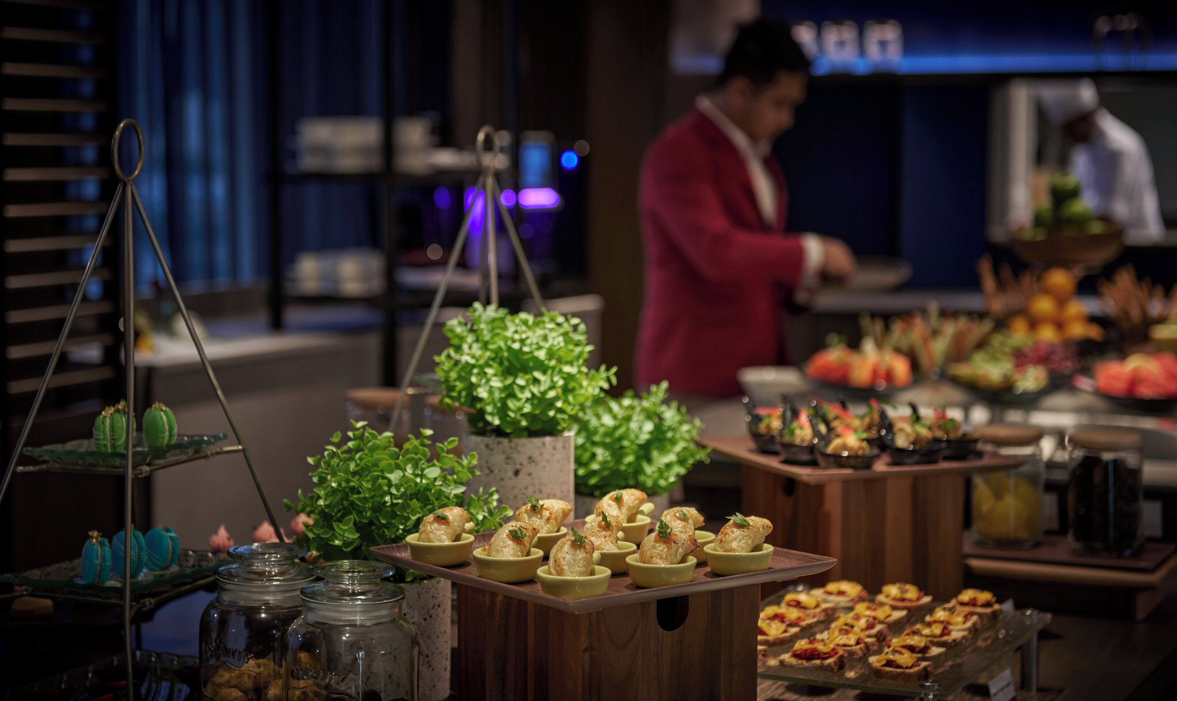 A buffet with various food items and a chef in the background.