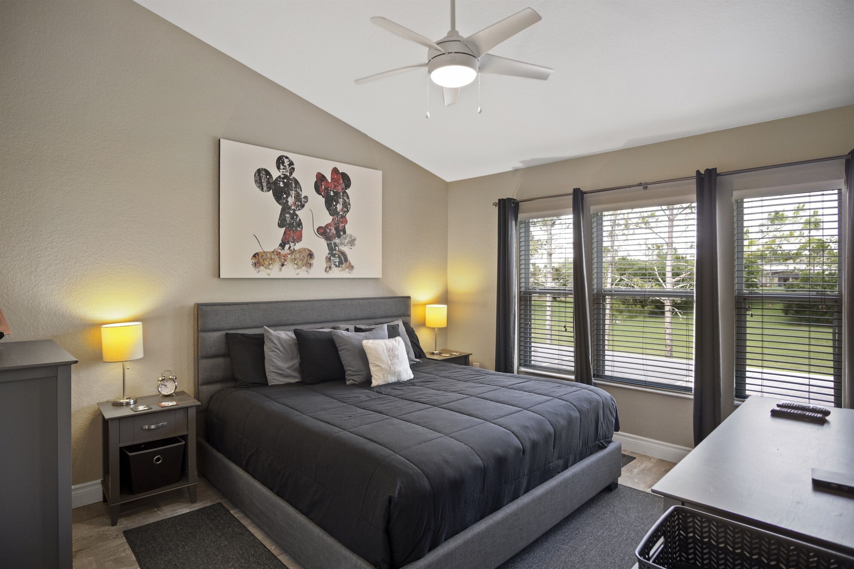 A bedroom with a bed, bedside tables, a ceiling fan, and a window with blinds.