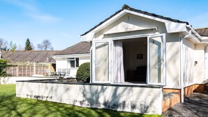 Ein eingeschossiges Haus mit einem großen Schiebeglastür, die zu einer überdachten Terrasse führt.