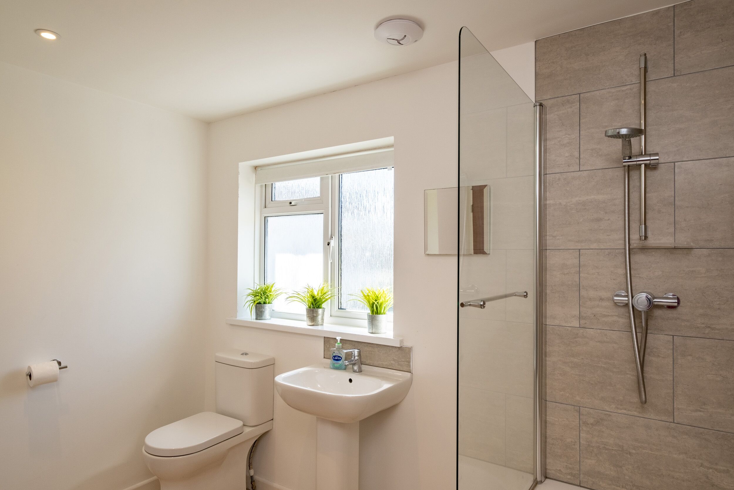Un baño moderno con inodoro, lavamanos y cabina de ducha de vidrio.