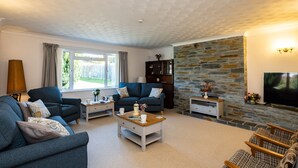 Ein Wohnzimmer mit Kamin aus Stein, zwei Sofas, einem Couchtisch und einem Fernseher.