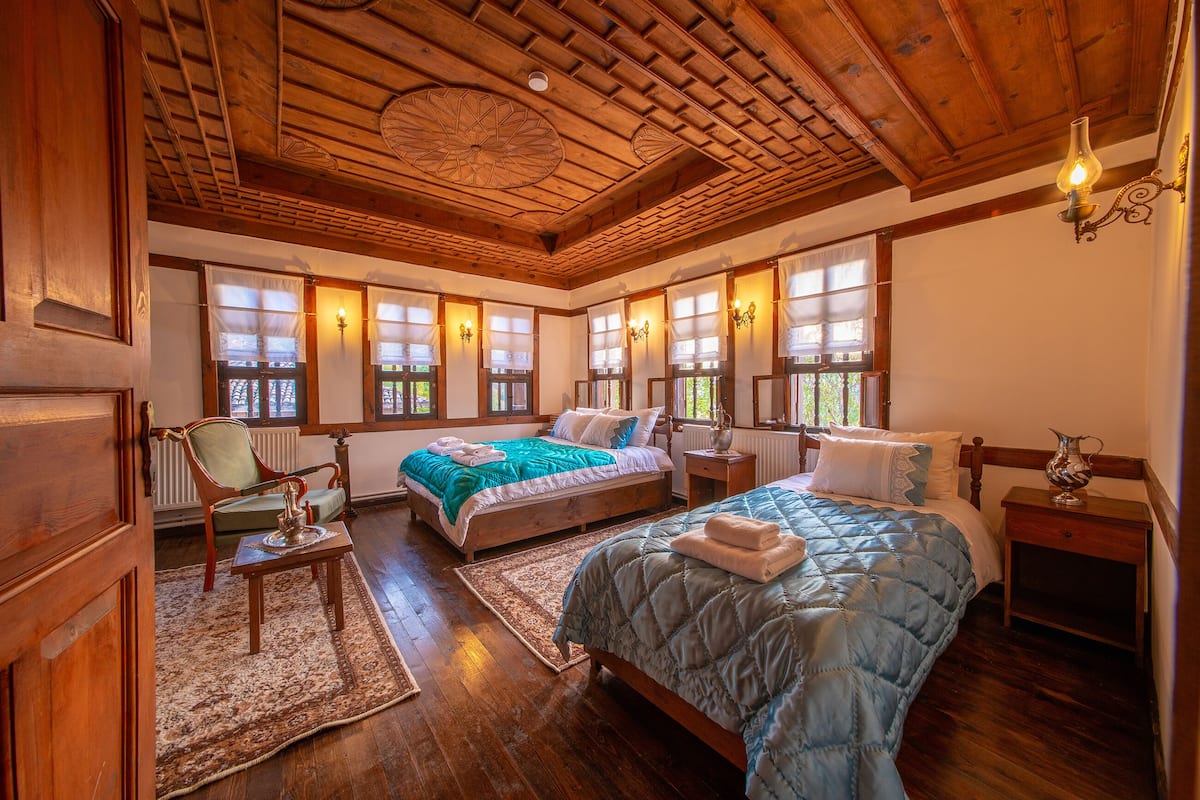 A spacious bedroom with wooden floors, a large bed, a chair, and a nightstand.