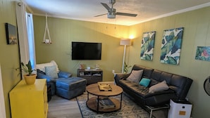 Un salon avec un canapé, une table basse et un téléviseur à écran plat.