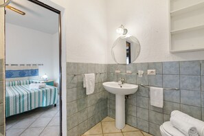 Un baño con cama, lavamanos y espejo.