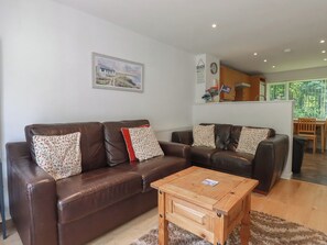 A living room with a brown leather sofa set, a wooden coffee table, and a framed picture on the wall. - 49 Atlantic Reach (Newquay)