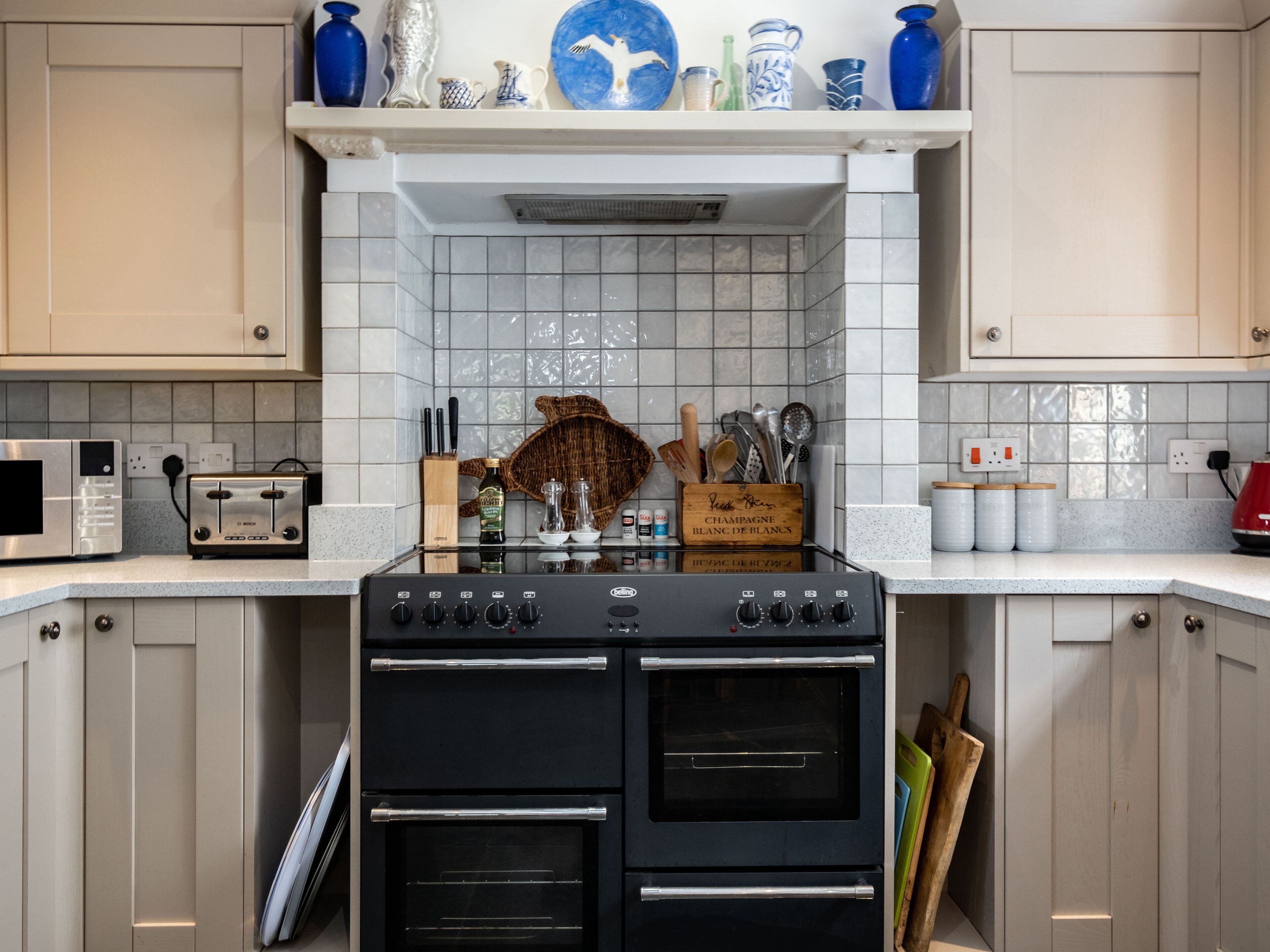 A kitchen with a black stove, white tiled backsplash, and various kitchen utensils on the counter.