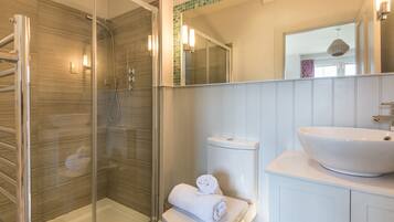 A modern bathroom with a glass-enclosed shower, a white toilet, and a large white sink.