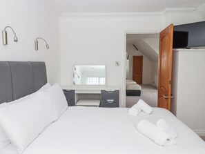 Una habitación de hotel con cama, escritorio, espejo y televisión.