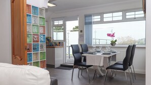 A dining area with a table set for four, chairs, a window with a view, and a colorful glass block wall.