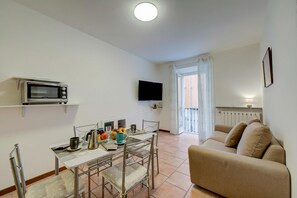 A compact living space with a kitchenette, a dining area, a sofa, and a TV mounted on the wall. - Casa Dolce Casa Stresa 50m From Lake (Stresa)