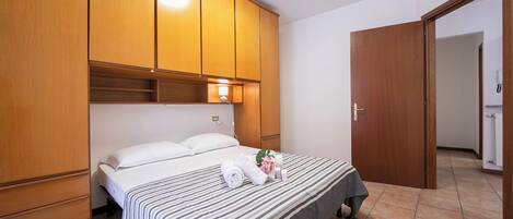 Ein Hotelzimmer mit Bett, Holzschrank und einem durchgegangenen Tür sichtbaren Badezimmer.