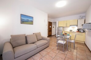 A living room with a sofa and a dining table with chairs. There is a kitchen area with cabinets and appliances. - Casa Dolce Casa Central Stresa Apt 50m From Lake (Stresa)