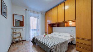 A bedroom with a bed, wooden wardrobe, a radiator, a small wooden chair, and a window with curtains. - Casa Dolce Casa Central Stresa Apt 50m From Lake (Stresa)