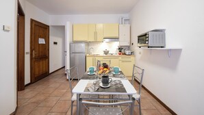 A compact kitchen with a dining table, chairs, and basic appliances. - Casa Dolce Casa Central Stresa Apt 50m From Lake (Stresa)