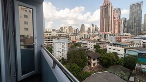A cityscape with high-rise buildings, a balcony with a door, and a view of the urban area. - Spark Hotel (Bangkok)