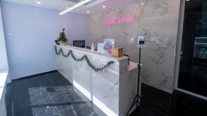 A hotel reception area with a marble counter, a Christmas tree, and a neon sign. - Spark Hotel (Bangkok)